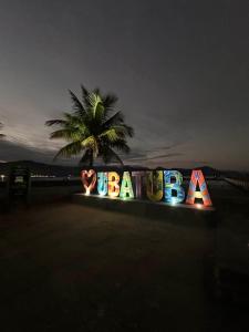 a sign for a beach with a palm tree in the background at Pousada Kasarão Praia Grande Ubatuba in Ubatuba