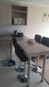 une cuisine avec une table, des chaises et un comptoir dans l'établissement Departamento Centro Chillán con estacionamiento, à Chillán 1 autre photo