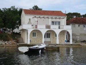 una barca in acqua davanti a una casa di Seaside holiday house Veli Rat, Dugi otok - 22718 a Sali (Sale)