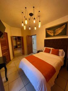 Un dormitorio con una cama grande y una lámpara de araña. en Hotel & Balneario Los Angeles en Taxco de Alarcón