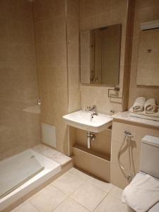 een badkamer met een wastafel, een douche en een bad bij Hôtels Jardy in Bab Ezzouar