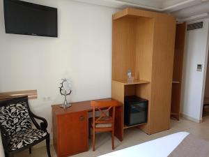 Habitación con escritorio, silla y TV. en Hôtels Jardy en Bab Ezzouar