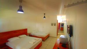 a small room with two beds and a television at El Currican Juan Dolio in Juan Dolio