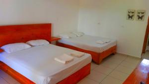two beds in a room with white sheets and towels at El Currican Juan Dolio in Juan Dolio