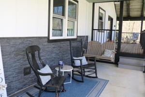 a porch with three rocking chairs and a table at Country Hills Hideaway in Millersburg