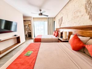 a hotel room with two beds and a flat screen tv at Grand Fifty Suites in Playa del Carmen