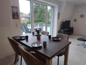 a dining room table with chairs and a large window at Ferienwohnung Windkunst in Norden