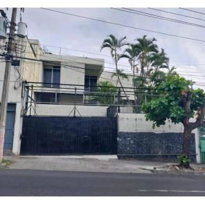 un edificio con una valla y un árbol delante de él en Gywel en San Salvador