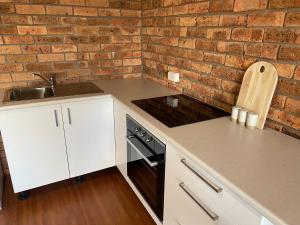 uma cozinha com armários brancos e uma parede de tijolos em Darcy’s Ranch em Bathurst