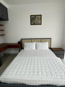 a bedroom with a bed with a white comforter at Căn hộ 2 phòng ngủ tầng 10 chung cư cao cấp Sophia Center in Ấp Rạch Mẹo