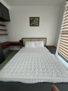 duże białe łóżko w pokoju z oknem w obiekcie Căn hộ 2 phòng ngủ tầng 10 chung cư cao cấp Sophia Center w mieście Ấp Rạch Mẹo