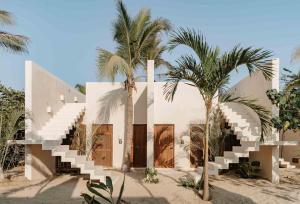 ein weißes Haus mit Palmen davor in der Unterkunft Casa Yuma, Puerto Escondido in Puerto Escondido