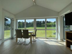 een eetkamer met een tafel, stoelen en ramen bij Ferienwohnung Hoherting in Prien am Chiemsee