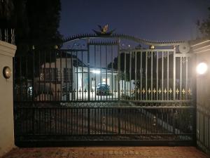 a black gate with a car behind it at night at Chevli Accomodation in Germiston