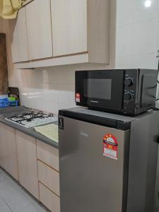a microwave on top of a refrigerator in a kitchen at Langkawi Perdana Families Suite @ Langkawi Airport in Pantai Cenang
