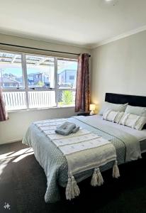 a bedroom with a large bed with a large window at Miami Stay in Auckland
