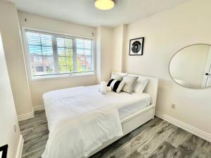 a white bedroom with a large bed with a mirror at Cozy house near HWY401 & Go station in Scarborough in Toronto