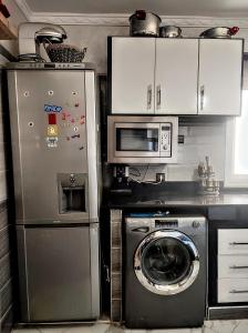 a kitchen with a washing machine and a microwave at Appartement luxe et confortable à côté de aswak in Oujda