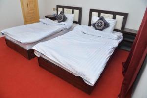 two beds in a room with white sheets and pillows at Tufail palace in Skardu