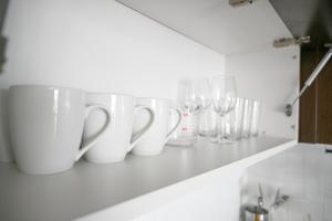 a row of white cups and wine glasses on a kitchen counter at Cozy 2B Apartment with great Amenities in the Heart of Cedar Park in Cedar Park +23 photos