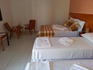 a hotel room with two beds and a table and chairs at Pousada Brisa Do Pontal in Fortim