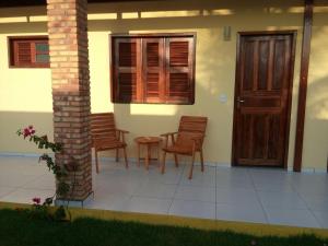 a porch of a house with chairs and a door at Pousada Brisa Do Pontal in Fortim