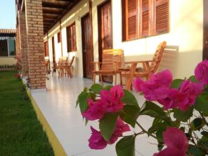 a porch of a house with pink flowers at Pousada Brisa Do Pontal in Fortim