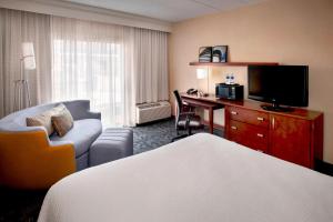 a hotel room with a bed and a desk with a television at Courtyard By Marriott Hartford Windsor Airport in Windsor