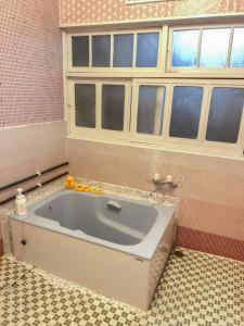 een badkamer met een bad en een raam bij Mojiko Guesthouse PORTO in Kitakyushu