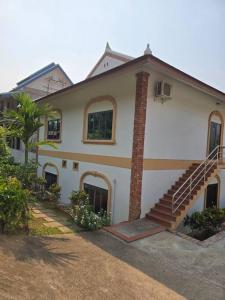 a white house with a staircase in front of it at #5 Appartement meublé + piscine. in Luang Prabang