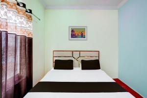 een slaapkamer met een wit bed met zwarte kussens bij OYO Flagship Vrindavan garden guest house and hotel in Kānpur