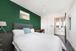a bedroom with a white bed with a green wall at Penthouse w/ Hot Tub near Stratford, Westfield in London