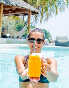 uma mulher de biquíni segurando uma bebida numa piscina em Orion Healing Centre em Srithanu