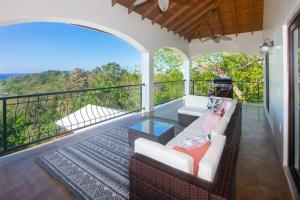 Apricari Villa / Luxury Views / 5 BDRM / Pool في رواتان: غرفة مع شرفة مع أريكة وطاولة