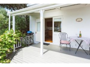 a white porch with a table and a chair at Romantic Cottage Recommended by NZ Herald in Oneroa