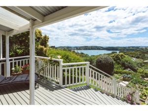 a white porch with a view of the water at Romantic Cottage Recommended by NZ Herald in Oneroa
