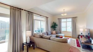 a living room with a couch and large windows at Al Dabas Beach Views, 3BD Sleeps 6, Beachfront Beach & Pool Access in Dubai