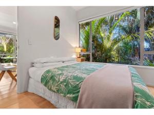 a bedroom with a bed and a large window at Bellbird Paradise- Waiheke Escapes in Onetangi