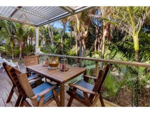 a wooden table and chairs on a porch with trees at Bellbird Paradise- Waiheke Escapes in Onetangi
