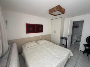Un dormitorio con una cama blanca y un baño. en Gran Lençóis Flat Residence, en Barreirinhas