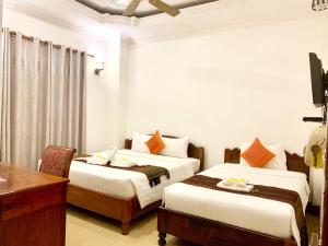 a hotel room with two beds and a desk and a desk at The One by Nika in Siem Reap