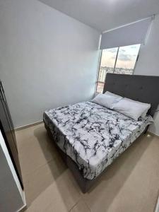 een bed in een witte kamer met een raam bij Lindo apartamento de 3 habitaciones in Cúcuta