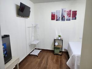 Habitación blanca con cama, TV y suelo de madera. en Gywel en San Salvador