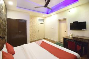 Super OYO Hotel Maa Residency في جامو: غرفة نوم مع سرير مع مروحة سقف ومكتب