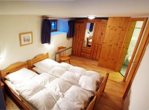 a large bed with white sheets in a room at Chalet Heimeli in Saas-Fee