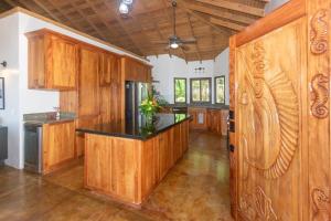 a kitchen with wooden cabinets and a black counter top at Apricari House Stunning Views 3 BDRM and Pool in Roatan