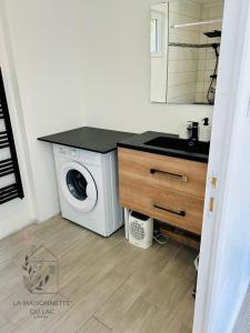 eine Waschküche mit einer Waschmaschine und einem Waschbecken in der Unterkunft Maison avec accès au lac in Izon