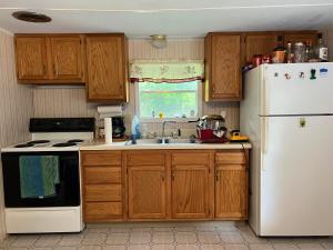 eine Küche mit Holzschränken und einem weißen Kühlschrank in der Unterkunft Bailey wick farm Jackson river retreat in Covington