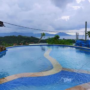 a large blue swimming pool with mountains in the background at Yoga bale house in Karangasem