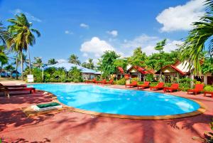 a swimming pool at a resort with chairs and trees at Lanta Emerald Bungalow in Ko Lanta
